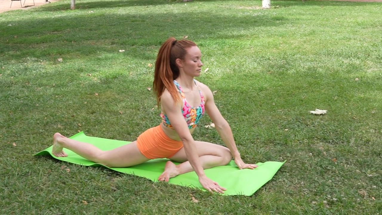 Uma mulher em roupa esportiva pratica alongamentos de yoga ao ar livre em meio à natureza serena para o bem-estar.