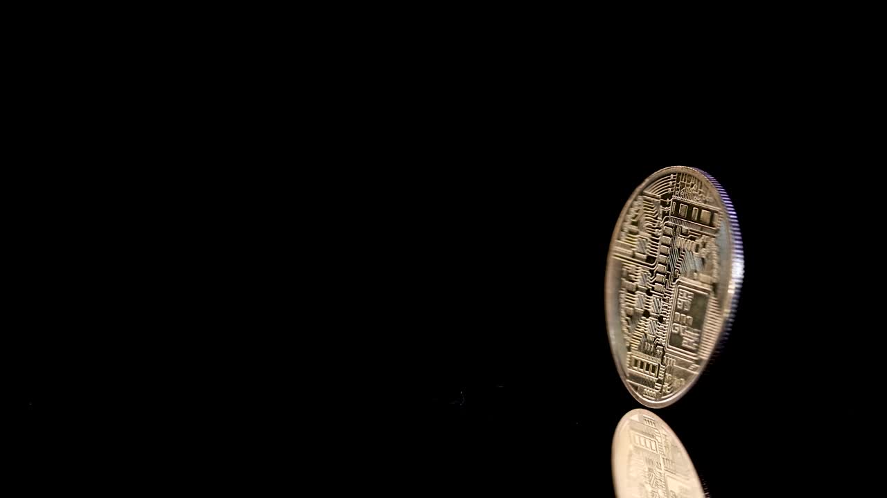 Golden cryptocurrency coin spins and lands on glossy black surface, dramatic lighting, slow motion