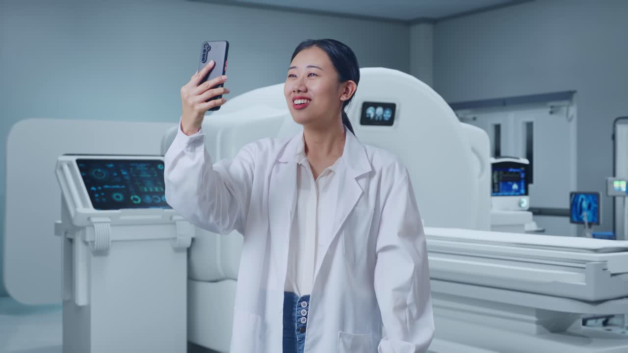 Asian Woman Doctor Waving Hand And Having A Video Call On Smartphone While Standing With Mri Machine In The Hospital