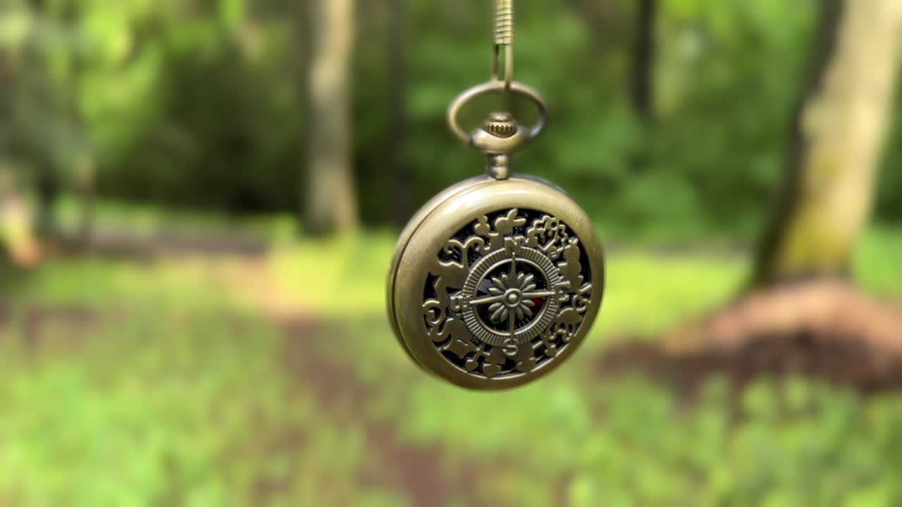 Antique pocket compass swinging from a chain in a forest in Romania