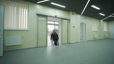 disabled woman in wheelchair at home comes in to modern office building