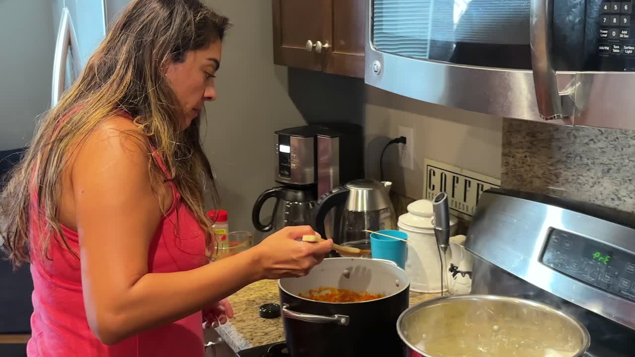 ama de casa hispana cocinando pasta y salsa en la cocina