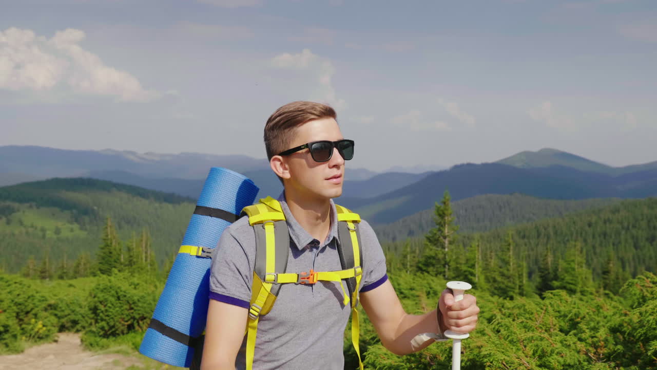 Genç bir turist, pitoresk bir manzara eşliğinde trekking batonları kullanarak dağa tırmanıyor.