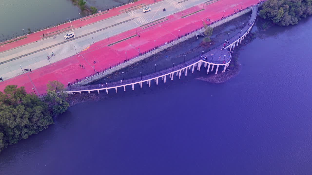 Aerial of a curved waterfront viewing deck beside a coastal road and calm waters in the Philippines. Ideal for travel, urban, and architectural visuals