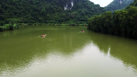 Drone-Siguiendo-Botes-A-Remo-Con-Turistas-En-El-Parque-De-Aves-Ninh-Binh