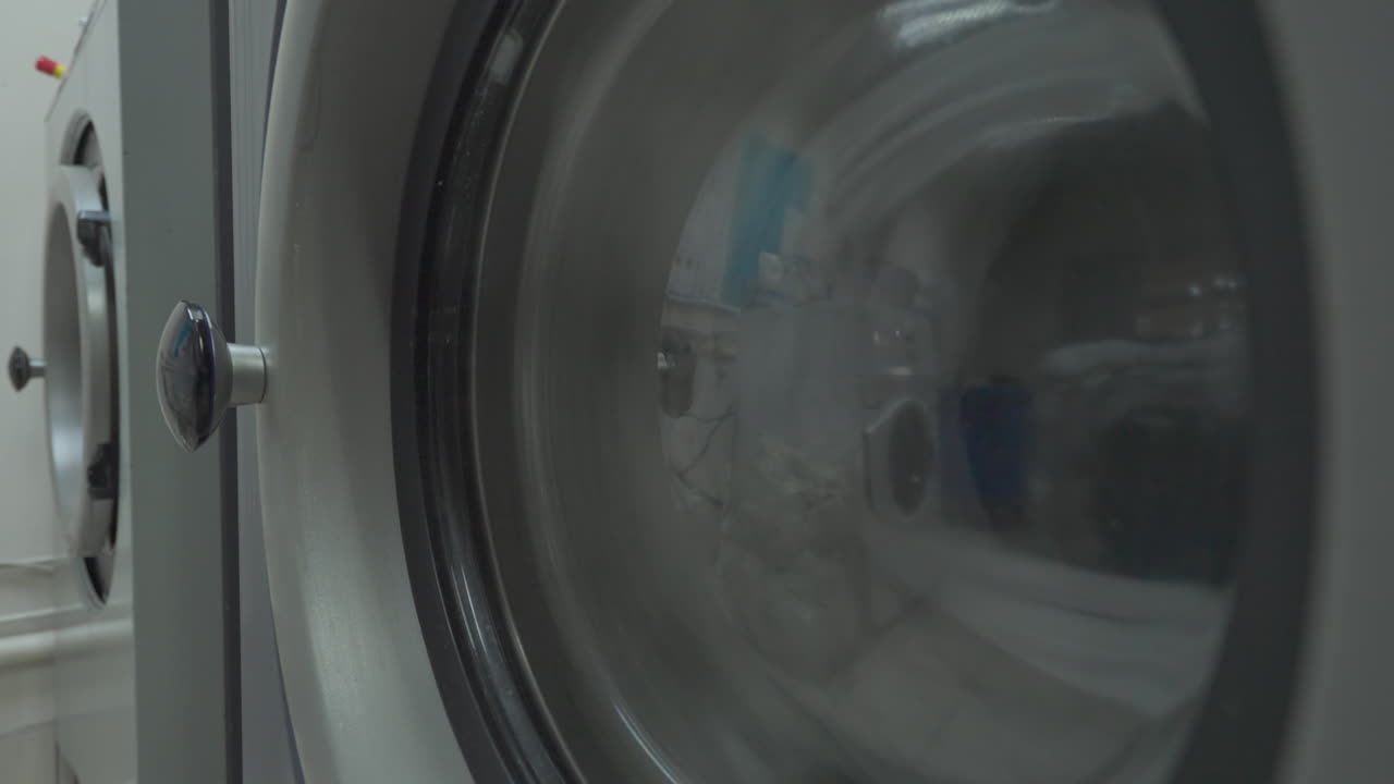 Detail průmyslové pračky v režimu odstřeďování v prádelně.
