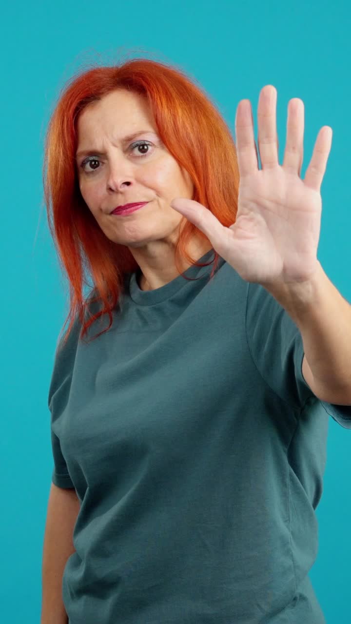 Woman showing a stop gesture with her hand against a blue background