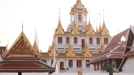 looking-up-at-towering-detailed-golden-pagoda-spires-in-a-buddhist-temple-complex-in-the-Rattanakosin-old-town-of-Bangkok,-Thailand