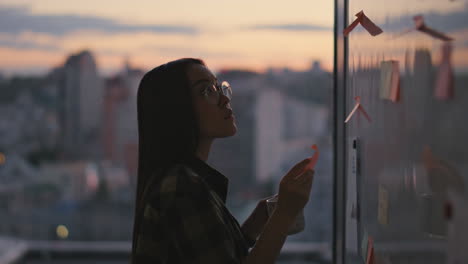 woman silhouette reading stickers at sunset office close up. girl applying notes