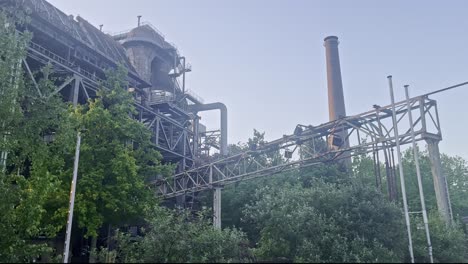 metalwork with steel struts and large brick chimney overgrown in nature