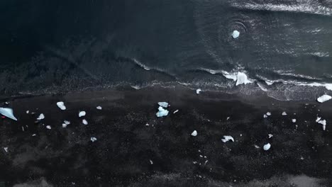 Luftaufnahme-Vom-Diamond-Beach-Im-Sommer-Islands,-Umgeben-Von-Schwarzem-Sand-Und-Wellen-Mit-Unglaublichen-Eisbergen-über-Der-Strandküste