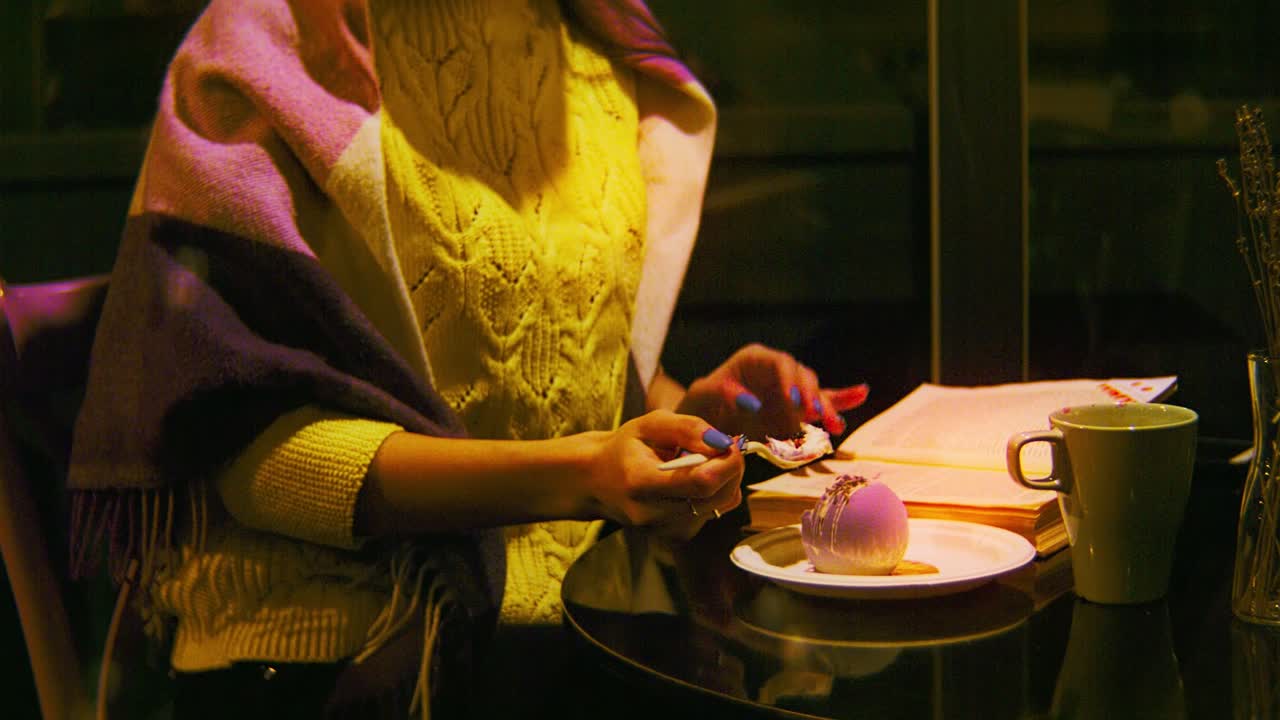 mujer comiendo postre en un acogedor café por la noche