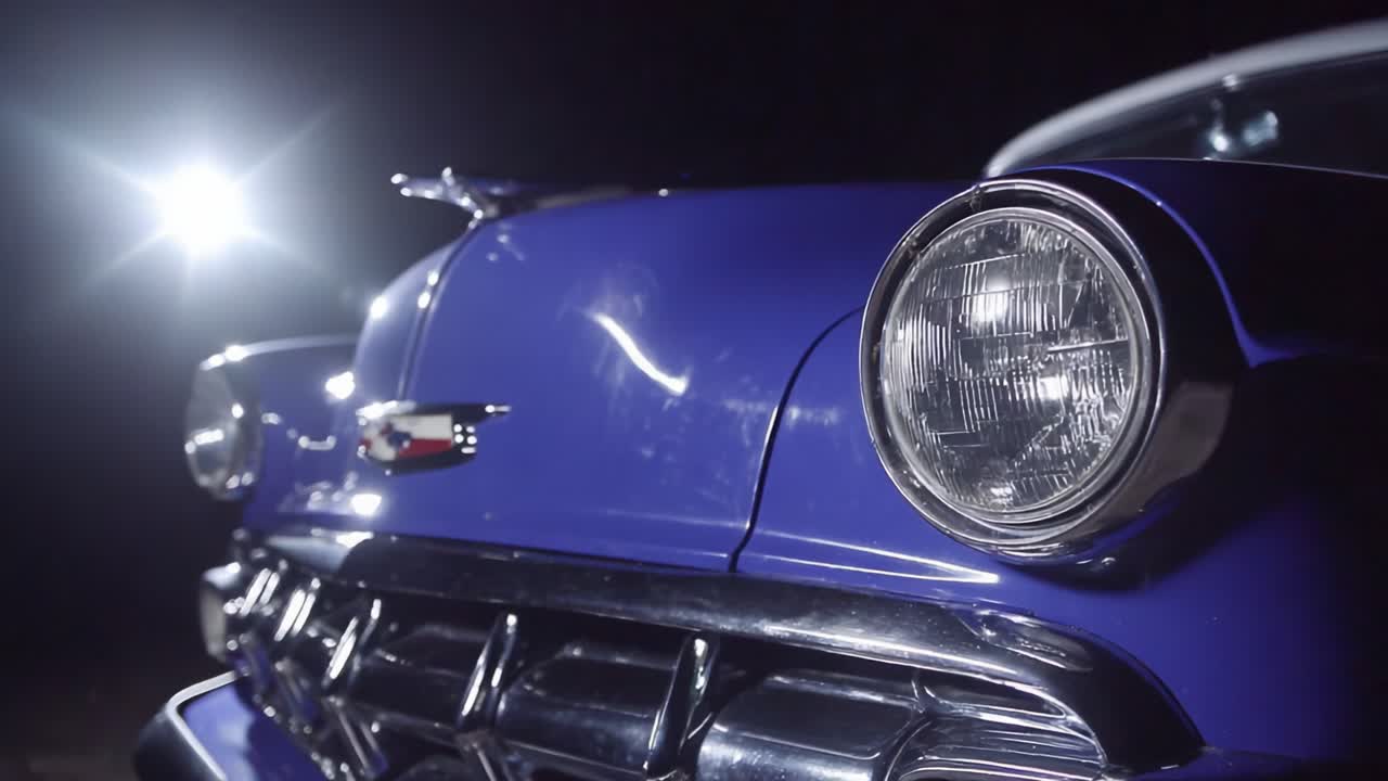 Eine Nahaufnahme eines klassischen, lilafarbenen Autos, das durch eine dramatische Beleuchtung hervorgehoben wird und seine glänzende Oberfläche und Vintage-Designmerkmale für AutoenthusiastInnen zur Schau stellt