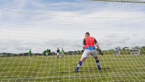 male and female soccer players playing soccer, shooting at goal with goalkeeper defending on pitch
