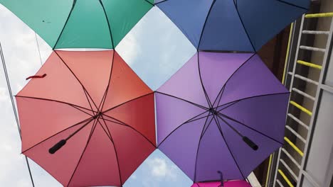 colorful row of umbrellas hanging in an alley in colombia, dolly in, looking up