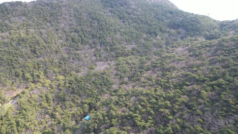 drone aerial view in south korea countryside flying in busan over a green and rocky mountain on a sunny day