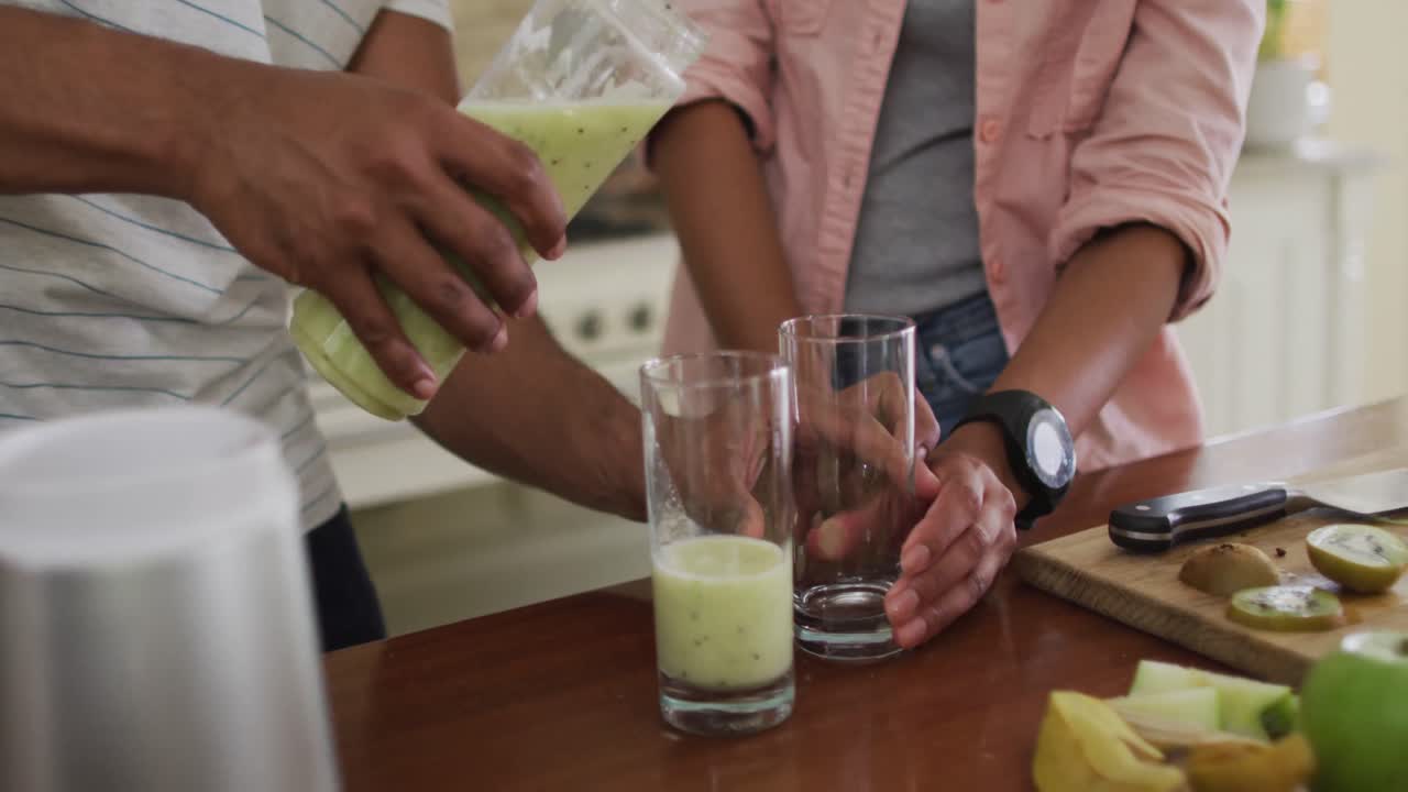 부 ⁇ 에서 스무디를 준비하는 두 인종의 부부의 손, 유리잔에  ⁇ 어