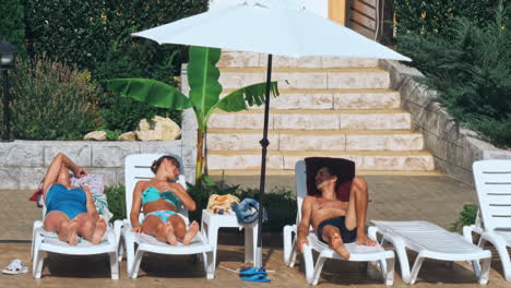 personas sentadas a la orilla de la piscina de un resort durante las vacaciones de verano