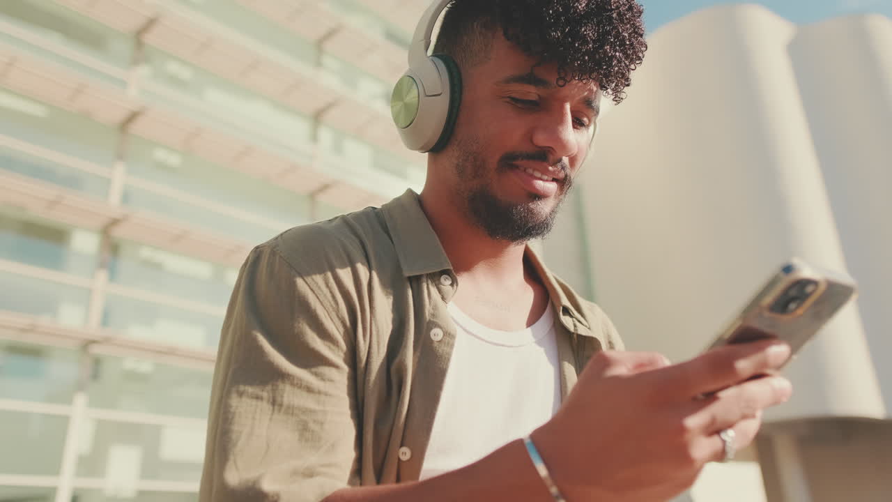 Uomo che ascolta la musica con le cuffie mentre usa il telefono all'aperto