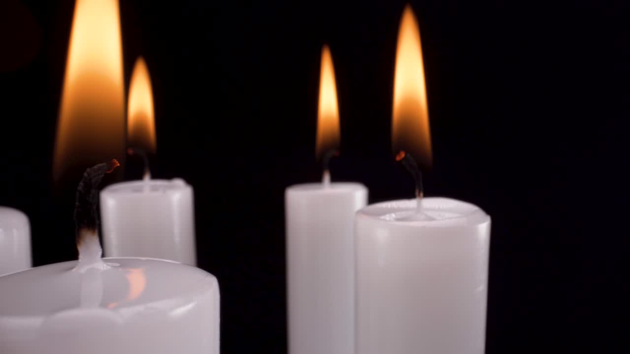 vista macro candele bianche rotanti su sfondo nero, ricordo elegante