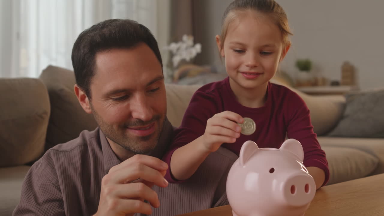 Father and Daughter Saving Money with a Piggy Bank at Home