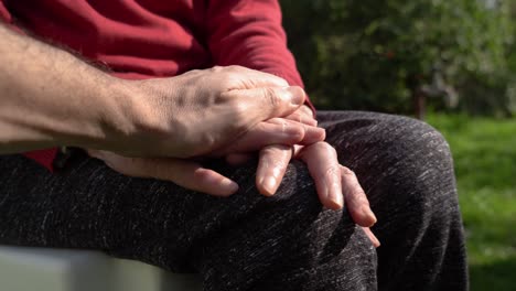 hombre adulto acariciando las manos de su madre envejecida afuera