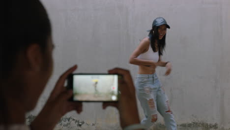 dancing woman happy freestyle dancer friend using smartphone taking video enjoying sharing hip hop dance on social media in grungy urban warehouse