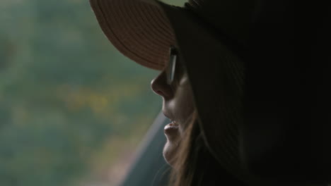 close up of woman wearing sunhat in car as car drives in slow motion