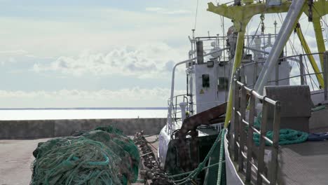 Mooring-tug-trawl-boat-docking-next-to-pile-of-rope-swarm-of-flies-in-bright-summer-day,-static