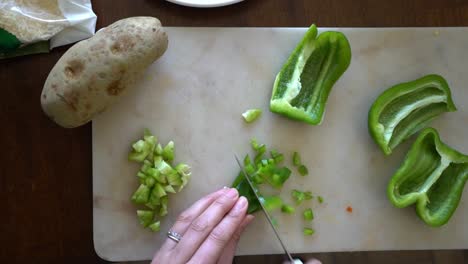 female chef chopping up green bell peppers as she prepares to cook dinner