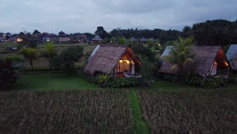 person relaxing in outdoor bathtub of cabin hut in rural balinese nature in the evening, drone shot