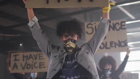 Diverse group of people wearing face masks holding protest signs