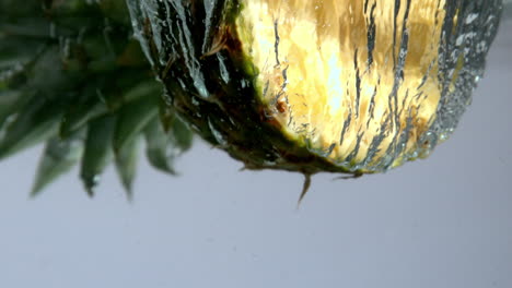 pineapple half falling in water on white background