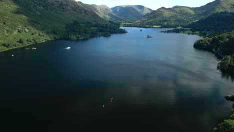 dark lake surrounded by wooded mountains with flight towards white ferry on bright summer day