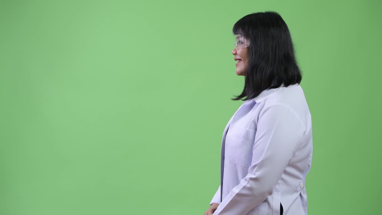 Profile view of beautiful Asian woman doctor wearing protective glasses