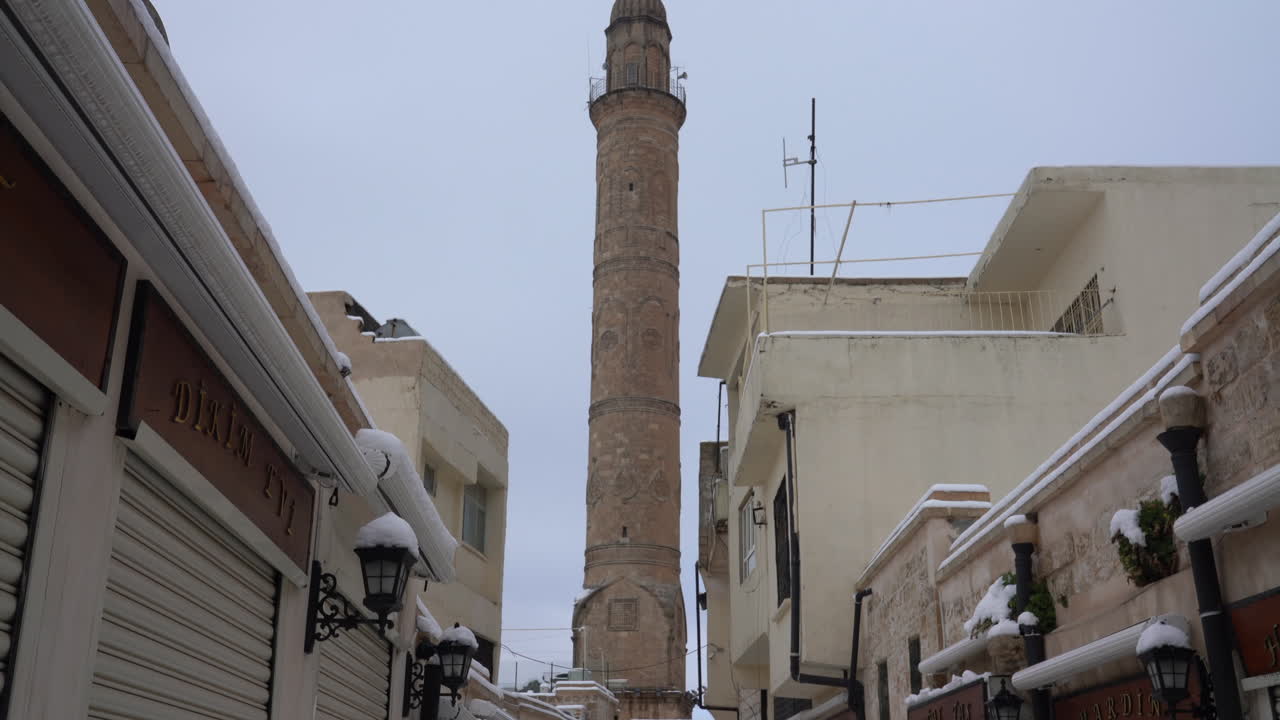 Vediamo il magnifico minareto della grande moschea sullo sfondo, tra i negozi allineati a destra e a sinistra nel bazar di Artuklu, nel centro storico di Mardin.