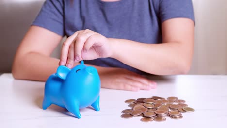 Woman-putting-coin-in-piggy-bank,-saving-money-concept