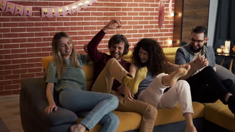 personas diversas en ropa casual en la sala de estar saltando en el sofá juntos y riendo