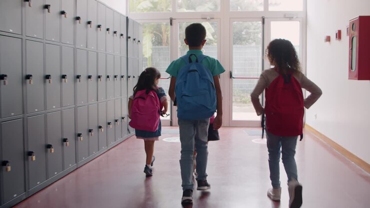 Grupo diverso de estudiantes de diferentes edades saliendo de la escuela