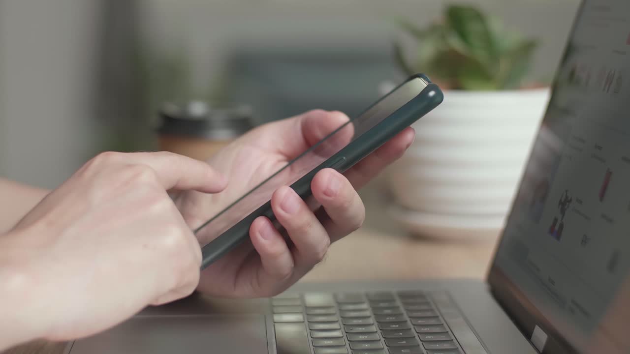 Hands Man Using Mobile Phone During Work On Laptop Computer, Video In 4K