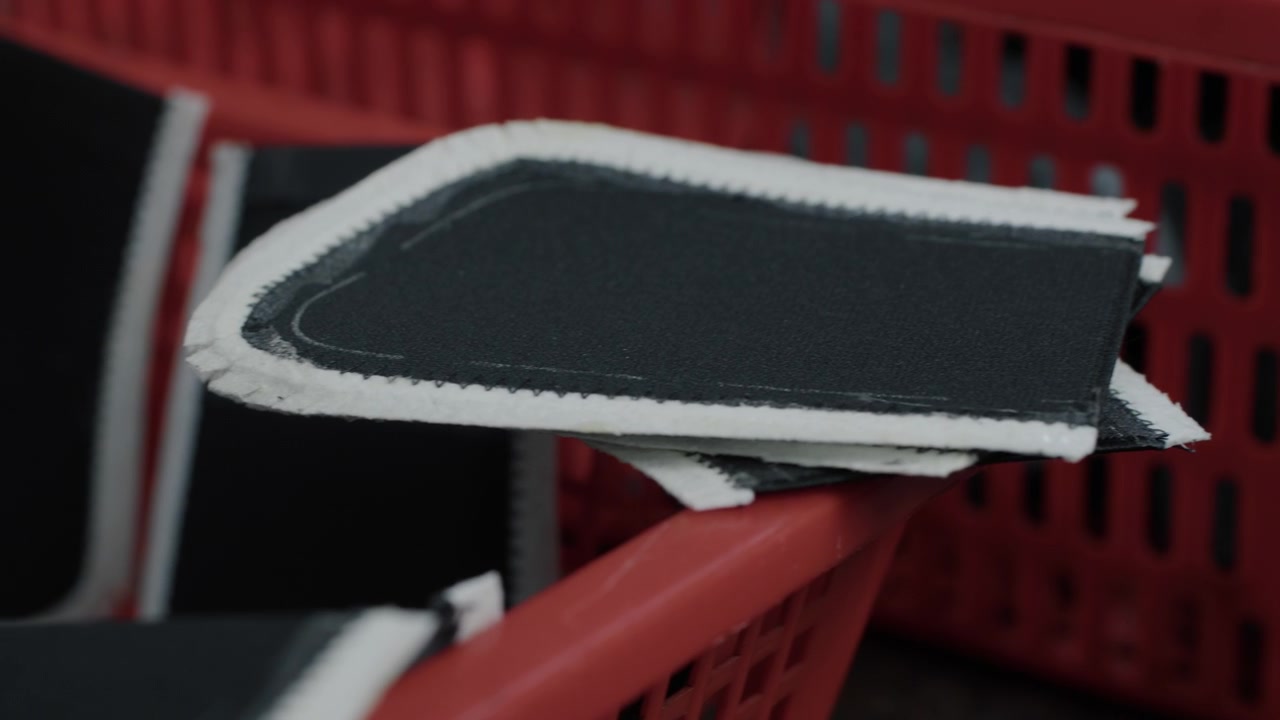 Shoe upper fabric pieces stacked in red baskets at a footwear production facility