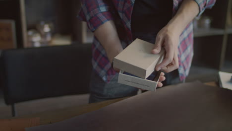 worker put leather wallet in product packaging box in small shop