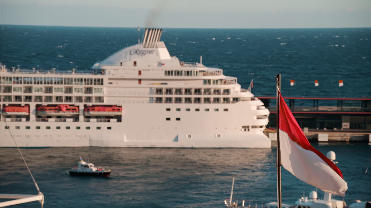 The flag of Monaco waving with a ship moving on the sea on the background