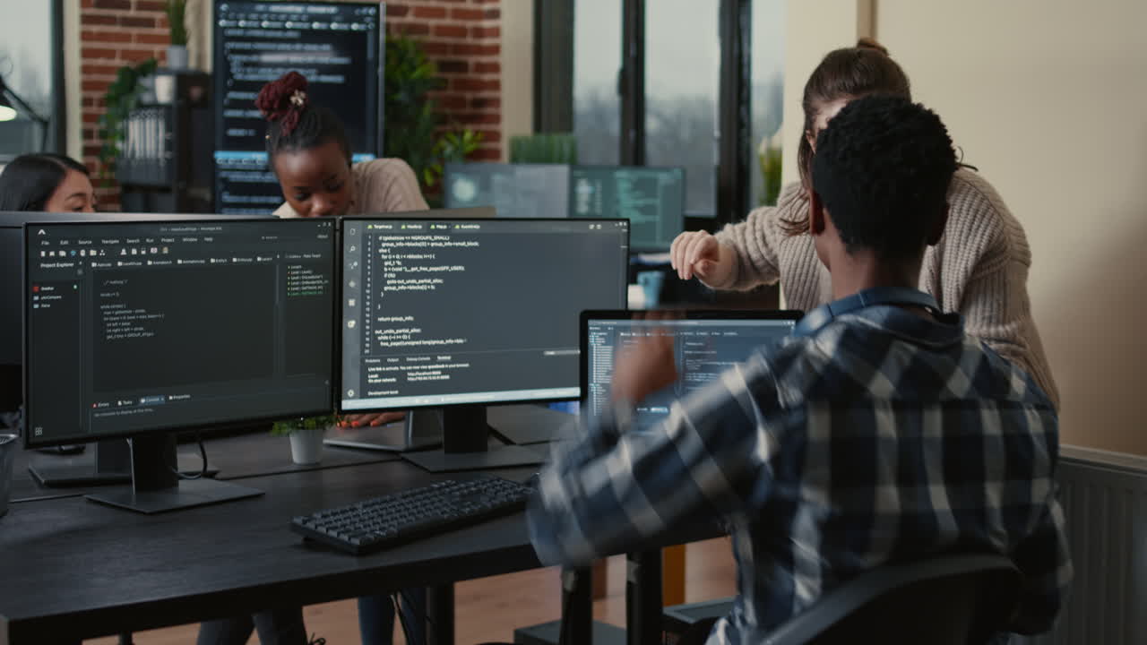 Software developer looking at running code on multiple screens takes off glasses and doing high five hand gesture