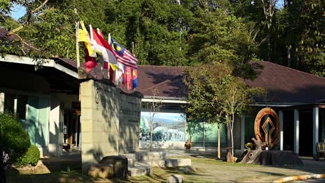 Nationalpark-Khao-Yai,-Besucherzentrum-Mit-Dem-UNESCO-Weltkulturerbe.-Sehr-Großes-Logo,-Während-Sich-Südostasiatische-Nationalflaggen-Im-Wind-Bewegen