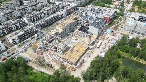 vista aérea de arriba hacia abajo en el techo de un edificio de apartamentos en construcción con una grúa de torre y muchos trabajadores colocando barras de metal
