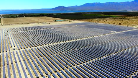 granja fotovoltaica de paneles solares aéreo de alto ángulo 4k drone retrocede y baja con el mar de salton en la distancia