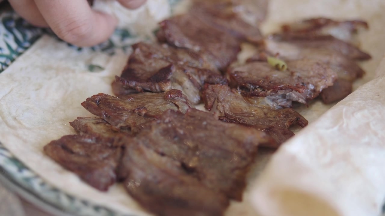 Persona che posiziona pezzi di carne alla griglia su pane lavash