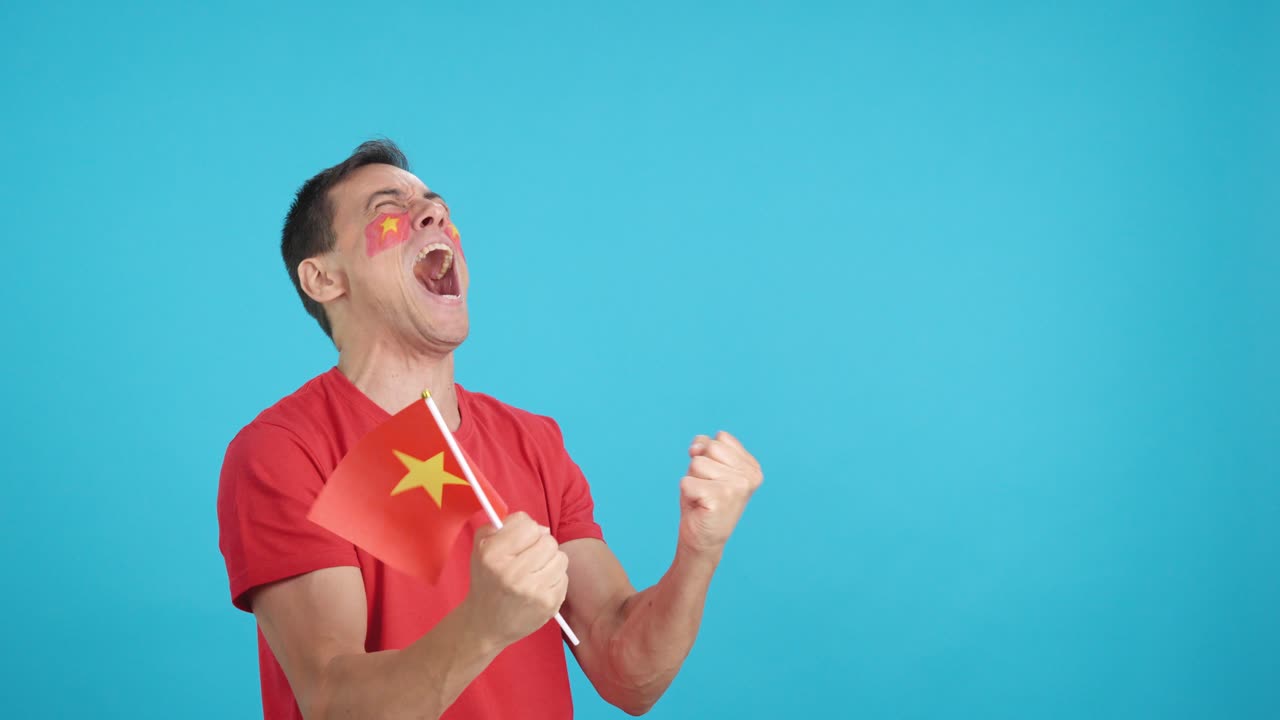 Man cheering for Vietnam waving a national flag looking away