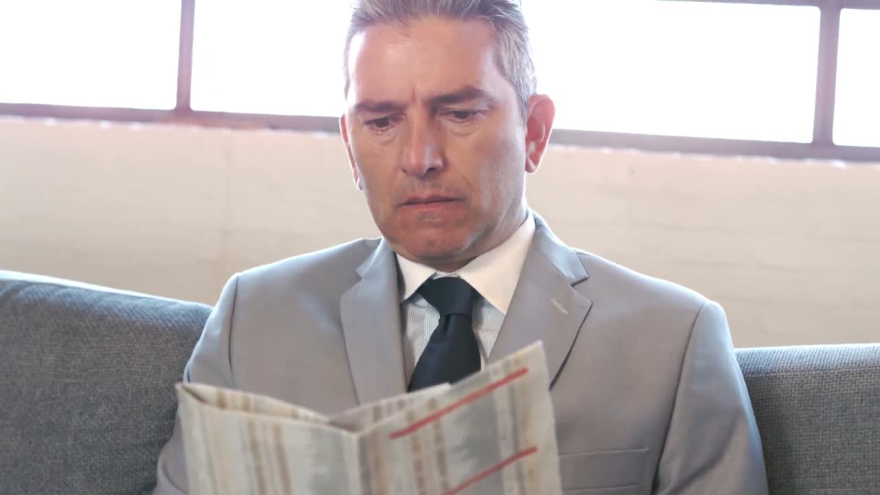 소파 에 앉아 신문 을 읽는 사업가